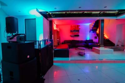 Cuisine moderne avec îlot central noir, chaises hautes, meubles rouges, électroménagers intégrés et carrelage blanc.