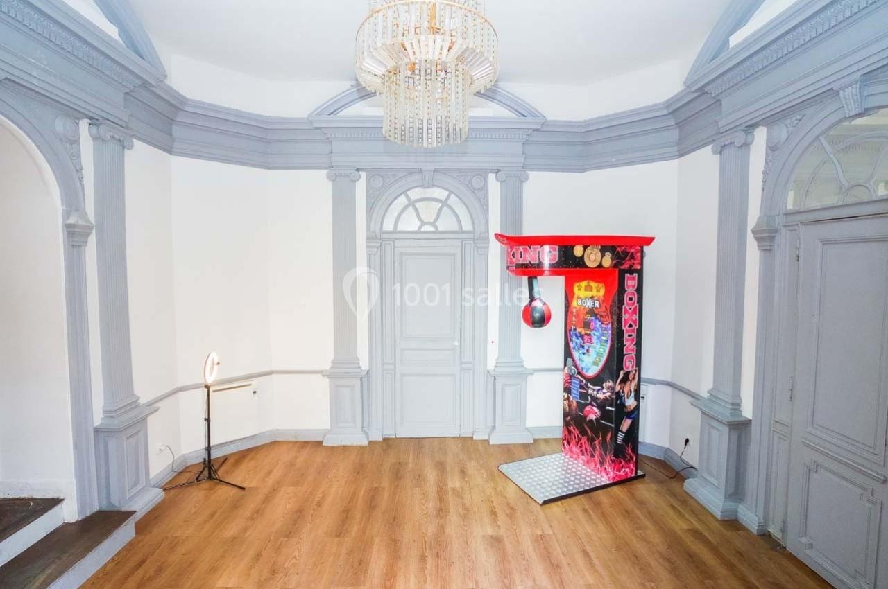 Machine de boxe rouge installée dans une pièce lumineuse avec parquet, murs blancs et moulures grises.