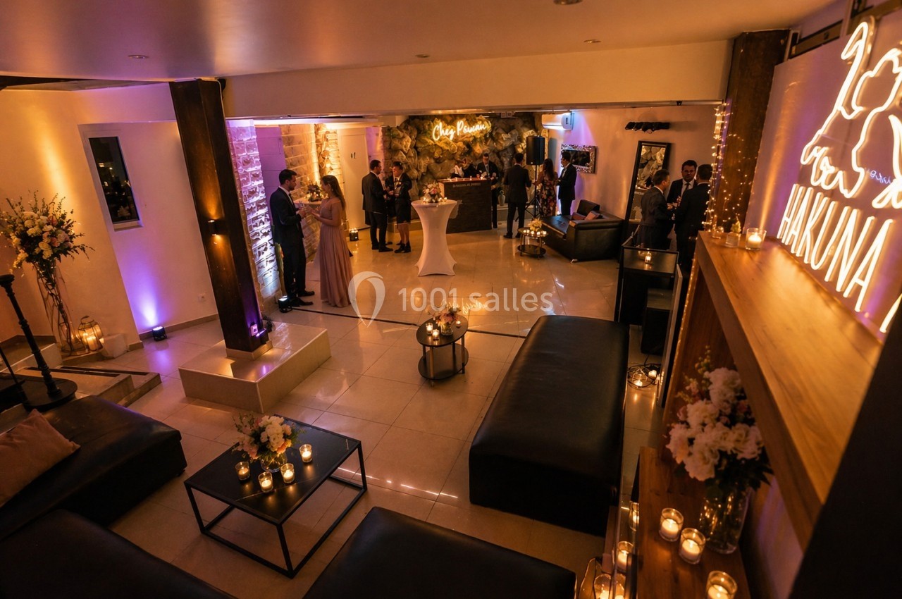 Location salle Nanterre (Hauts-de-Seine) - Manoir Loft 92 #9 Salle de réception chaleureuse avec éclairage tamisé, décor floral, bougies et invités discutant près du bar.