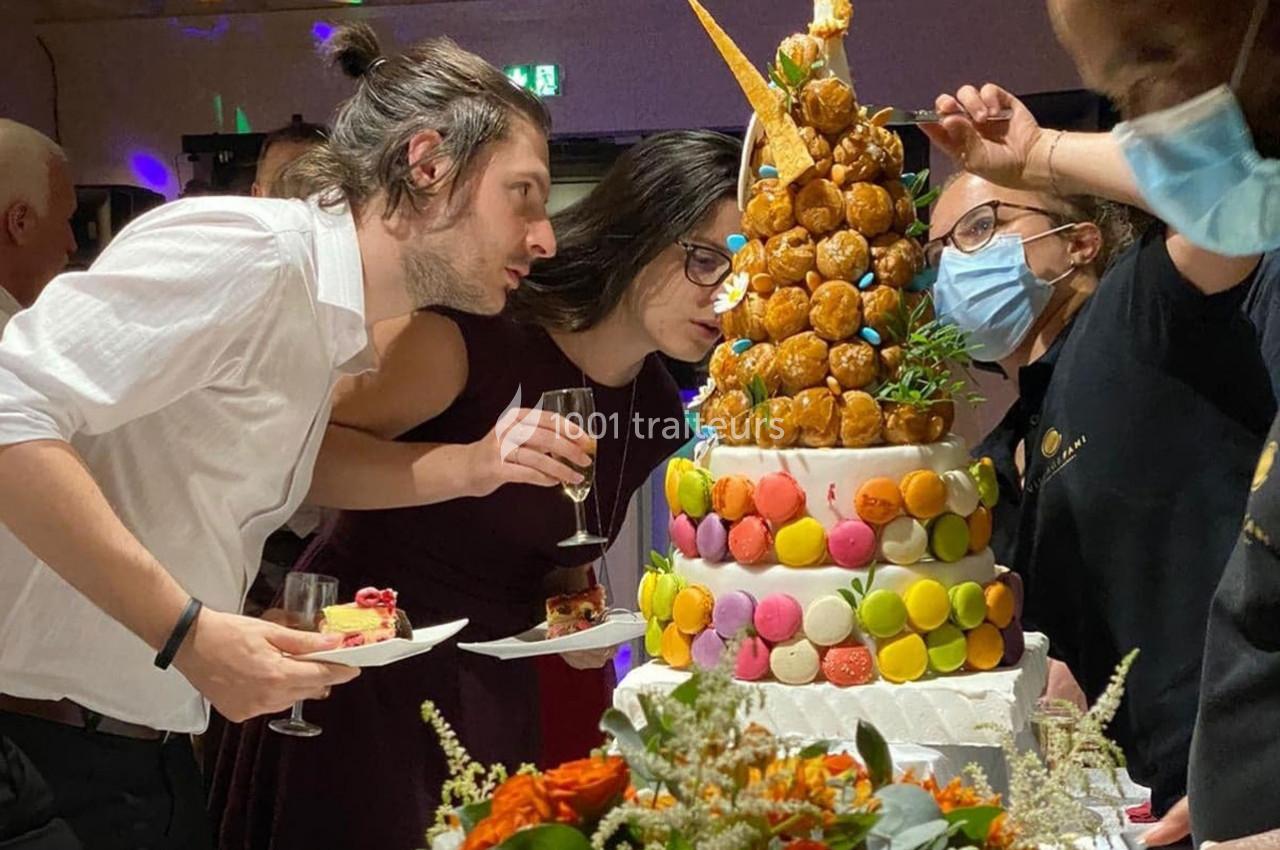 Des personnes observent une pièce montée décorée de macarons et de choux lors d'une réception festive.