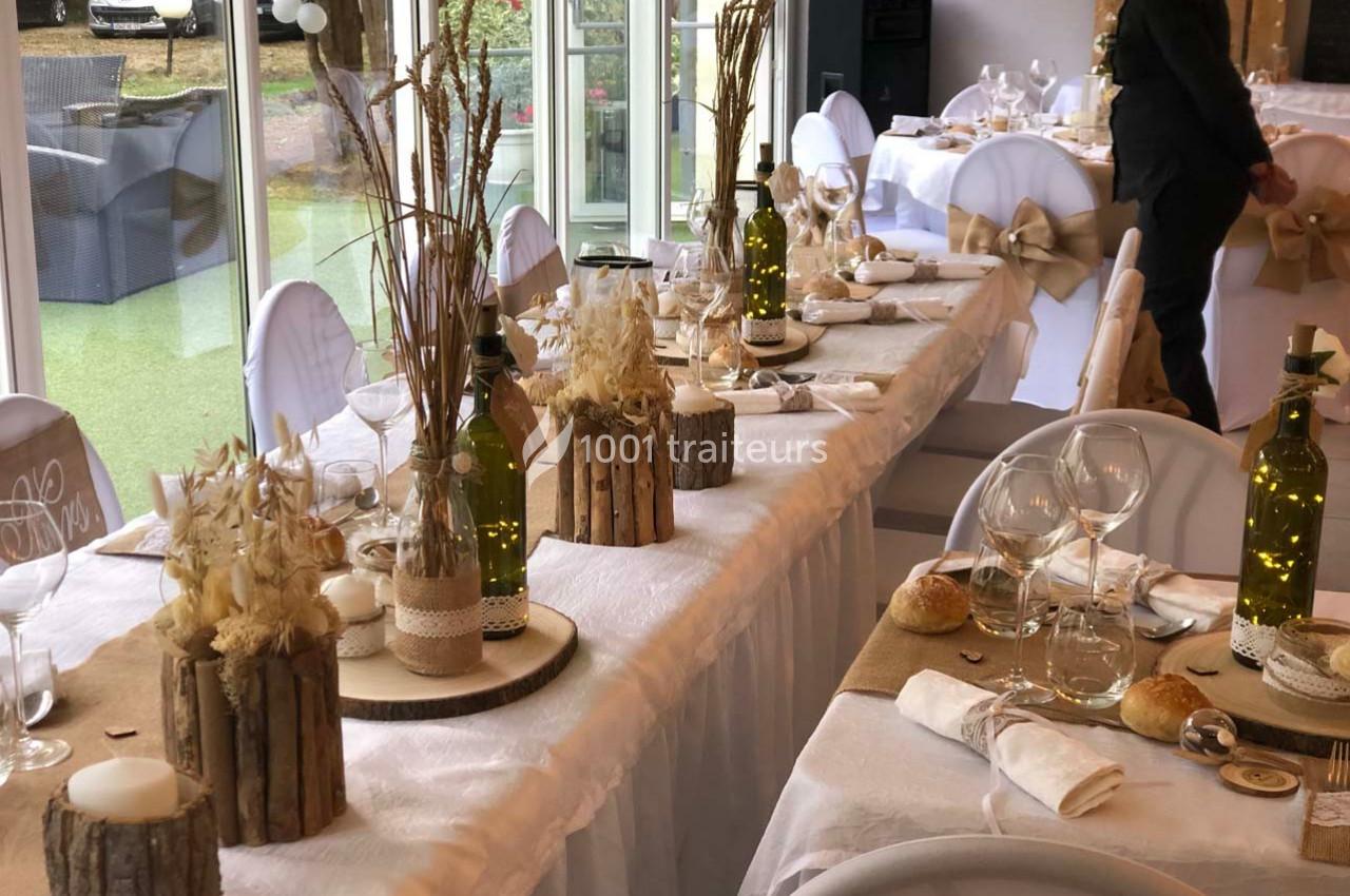 Salle de réception décorée avec des tables dressées, ornées de centres de table rustiques et d'éléments naturels.