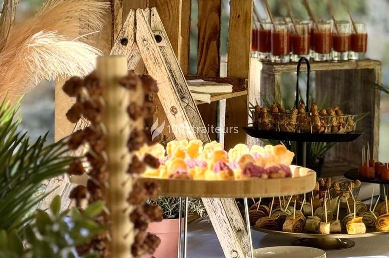 Buffet avec des amuse-bouches variés présentés sur des plateaux en bois, décoré de plantes et d'éléments naturels.
