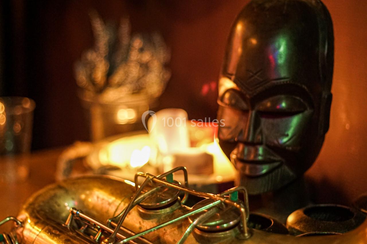 Saxophone doré posé sur une table en bois, avec une sculpture africaine et des bougies en arrière-plan.