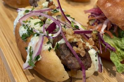 Plateau de mini-burgers au pain brioché, garnis de viande et de légumes colorés.