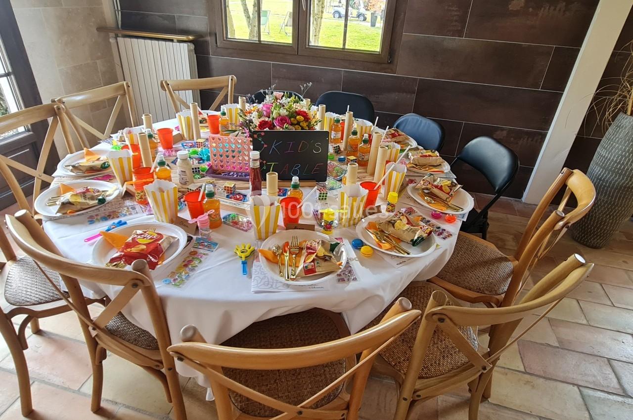 Table ronde décorée pour une fête d'enfants, avec assiettes, gobelets colorés, jouets et friandises.