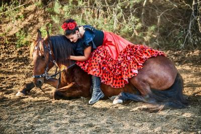 Une femme crache du feu dans l'obscurité, tenant une torche allumée, avec un cheval en arrière-plan.