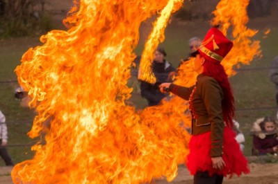 Femme en tenue traditionnelle caressant un cheval brun harnaché, dans un environnement naturel verdoyant.
