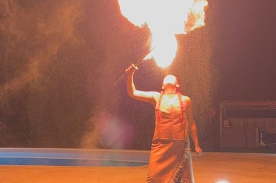 Femme en tenue traditionnelle caressant un cheval brun harnaché, dans un environnement naturel verdoyant.
