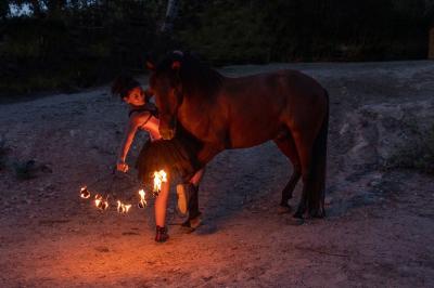 Une femme jongle avec des anneaux enflammés lors d'une performance nocturne en extérieur.