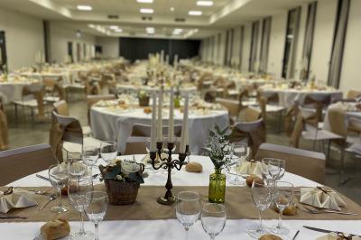 Table décorée pour un événement avec chandelier, fleurs, nappes blanches et vaisselle disposée élégamment.