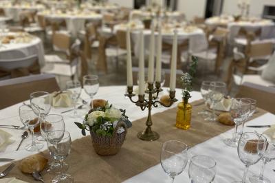 Table décorée pour un événement avec chandelier, fleurs, nappes blanches et vaisselle disposée élégamment.