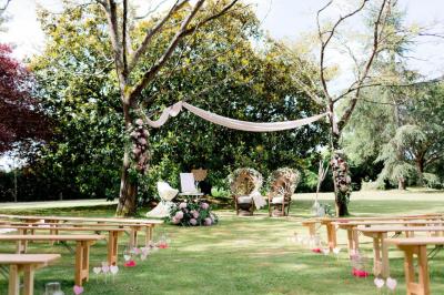 Salle de réception sous une tente avec tables dressées, décorations florales et éclairage suspendu.