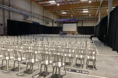 Salle de réception sous une tente avec tables dressées, décorations florales et éclairage suspendu.