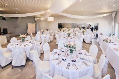 Miniature Location salle Charleroi (Hainaut) - Salles Belidanza #6 Salle de réception décorée avec des tables rondes, nappes beige, chaises ornées de nœuds et compositions florales.