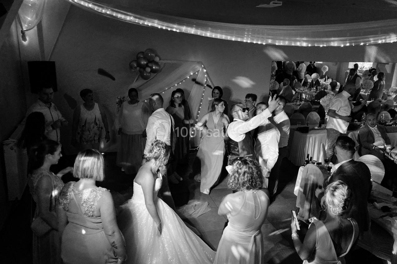 Des invités dansent et célèbrent autour des mariés dans une salle décorée pour une réception de mariage.