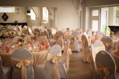 Miniature Location salle Charleroi (Hainaut) - Salles Belidanza #21 Salle de réception décorée avec des tables rondes, nappes beige, chaises ornées de nœuds et compositions florales.