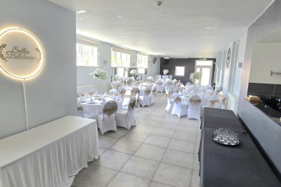 Miniature Location salle Charleroi (Hainaut) - Salles Belidanza #14 Salle de réception décorée avec des tables rondes, nappes beige, chaises ornées de nœuds et compositions florales.