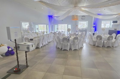 Miniature Location salle Charleroi (Hainaut) - Salles Belidanza #5 Salle de réception décorée avec des tables rondes, nappes beige, chaises ornées de nœuds et compositions florales.