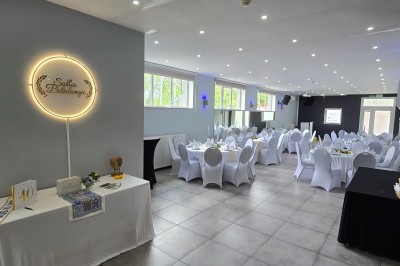 Miniature Location salle Charleroi (Hainaut) - Salles Belidanza #15 Salle de réception décorée avec des tables rondes, nappes beige, chaises ornées de nœuds et compositions florales.