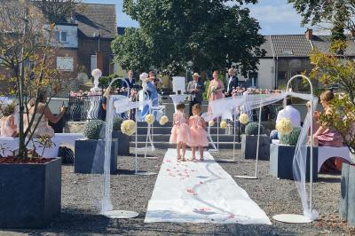 Miniature kiosque Salle de réception décorée avec des tables rondes, nappes beige, chaises ornées de nœuds et compositions florales.