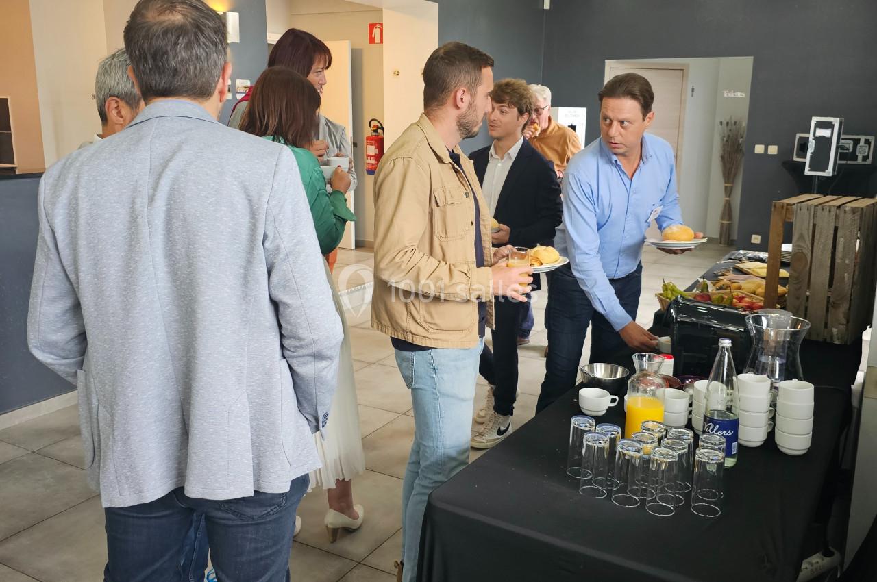 Des personnes se servent à un buffet dans un espace intérieur lumineux avec des boissons et des aliments disposés sur une…