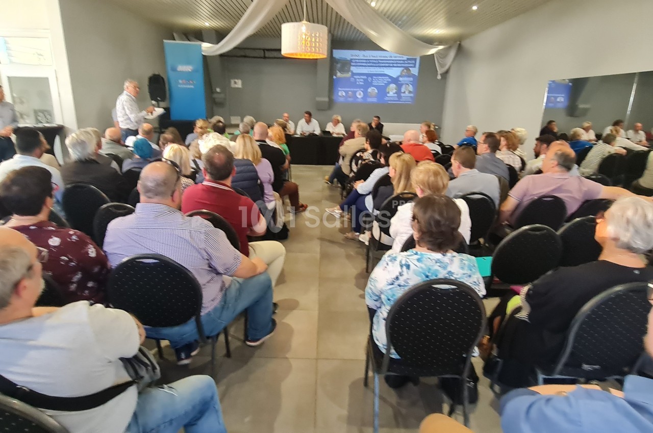 Salle comble avec des personnes assises écoutant un intervenant lors d'une réunion ou conférence.
