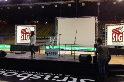 Salle de réception avec tables dressées et invités, éclairée par des lumières colorées et des motifs projetés au sol.