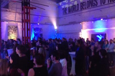 Salle de réception avec tables dressées et invités, éclairée par des lumières colorées et des motifs projetés au sol.