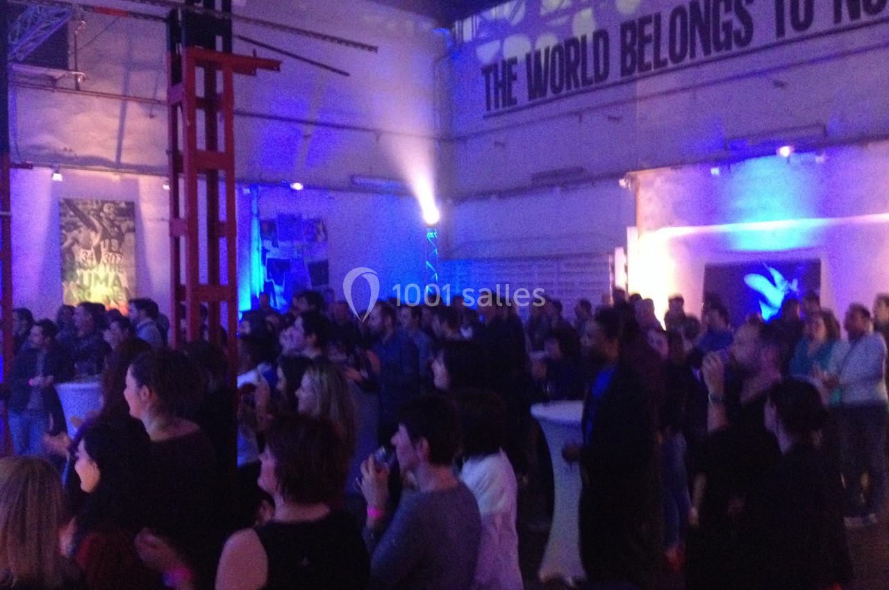 Groupe de personnes debout dans une salle éclairée de lumières bleues, semblant assister à un événement.