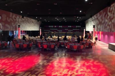 Salle de réception avec tables dressées et invités, éclairée par des lumières colorées et des motifs projetés au sol.
