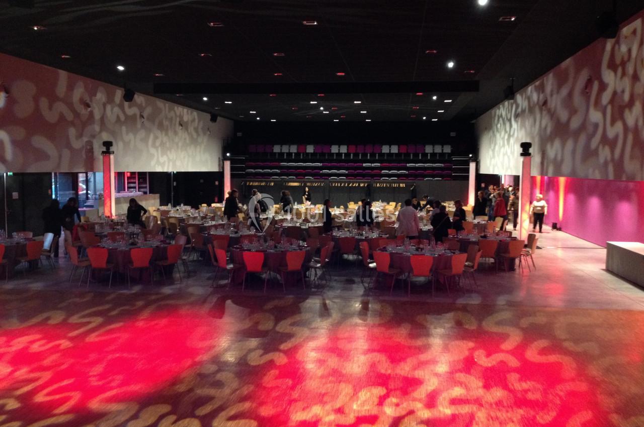 Salle de réception avec tables dressées et invités, éclairée par des lumières colorées et des motifs projetés au sol.