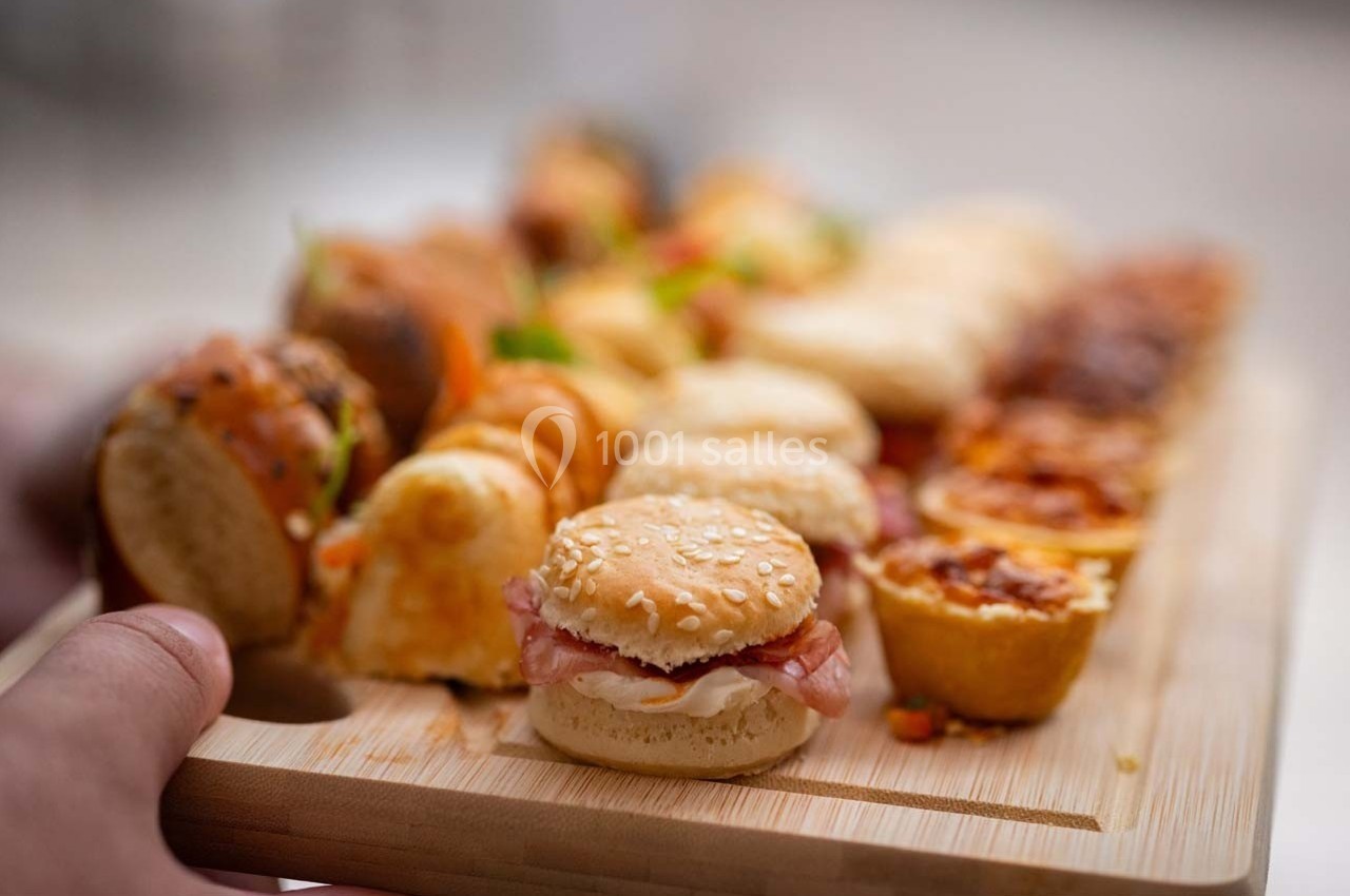 Plateau en bois garni de mini-sandwichs, bouchées salées et amuse-bouches variés.