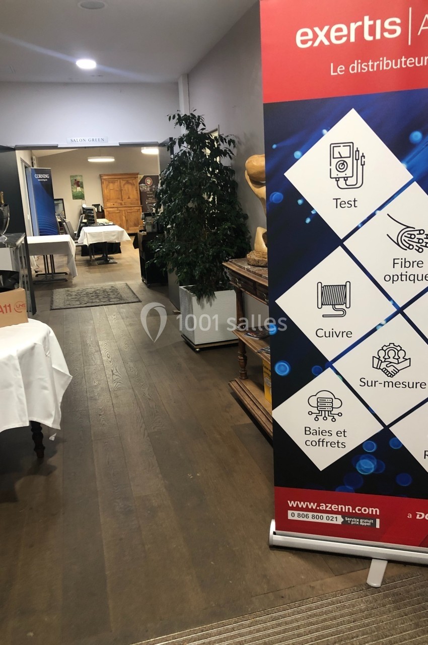 Bannière promotionnelle d'une entreprise dans un couloir avec des tables, des plantes et des affiches en arrière-plan.