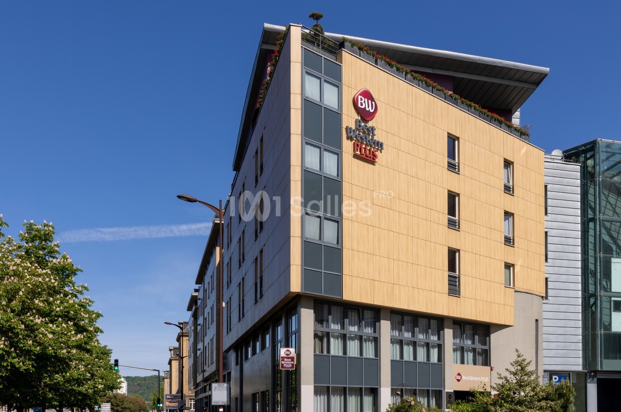 Façade d'un bâtiment moderne en bois clair avec des fenêtres, sous un ciel bleu dégagé.
