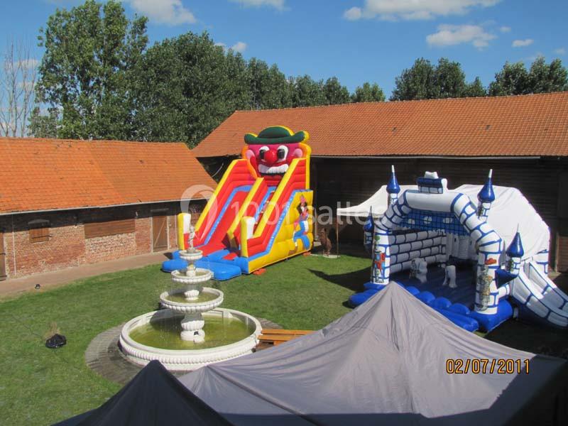 Deux structures gonflables colorées installées dans une cour avec une fontaine centrale et des bâtiments en arrière-plan.