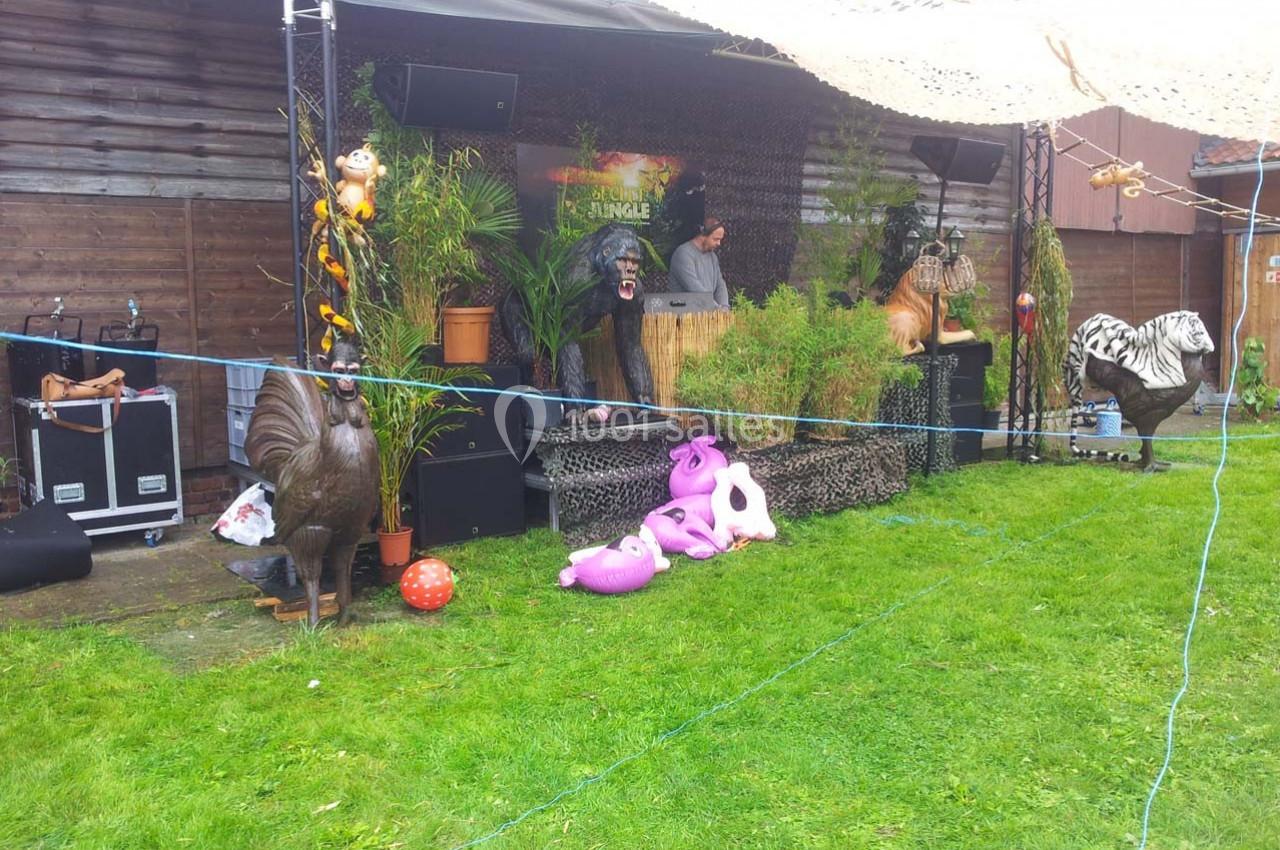 Un stand décoré sur le thème de la jungle avec des statues d'animaux et un DJ en arrière-plan.