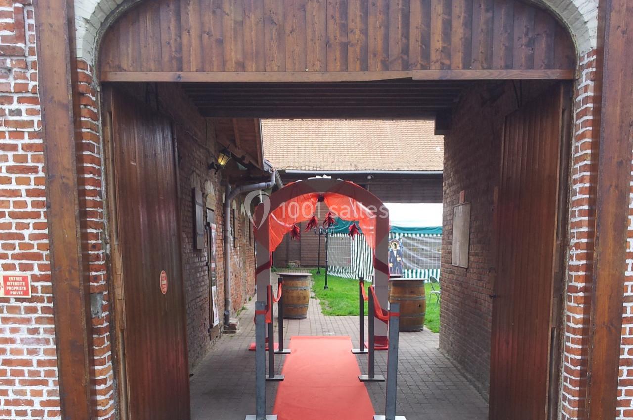 Entrée décorée avec un tapis rouge et une arche rouge dans une cour intérieure en briques.