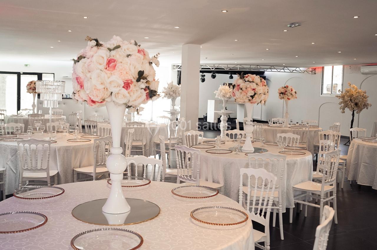 Location salle Roquevaire (Bouches-du-Rhône) - Nao Athéna #3 Salle de réception décorée avec des tables rondes, nappes blanches, chaises assorties et centres de table fleuris.