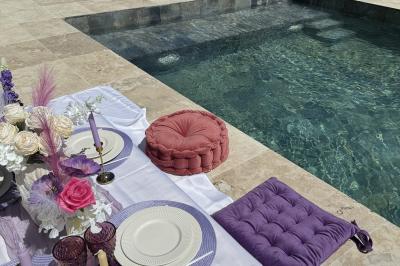 Miniature Location salle Roquevaire (Bouches-du-Rhône) - Nao Athéna #8 Table dressée avec vaisselle et fleurs bleues près d'une piscine entourée de dalles claires et de végétation.