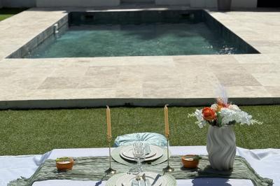 Miniature Location salle Roquevaire (Bouches-du-Rhône) - Nao Athéna #10 Table dressée avec vaisselle et fleurs bleues près d'une piscine entourée de dalles claires et de végétation.