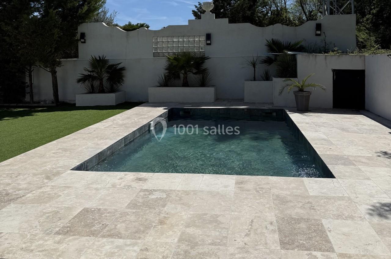 Location salle Roquevaire (Bouches-du-Rhône) - Nao Athéna #15 Piscine rectangulaire entourée de dalles claires, avec des plantes et un mur blanc en arrière-plan.