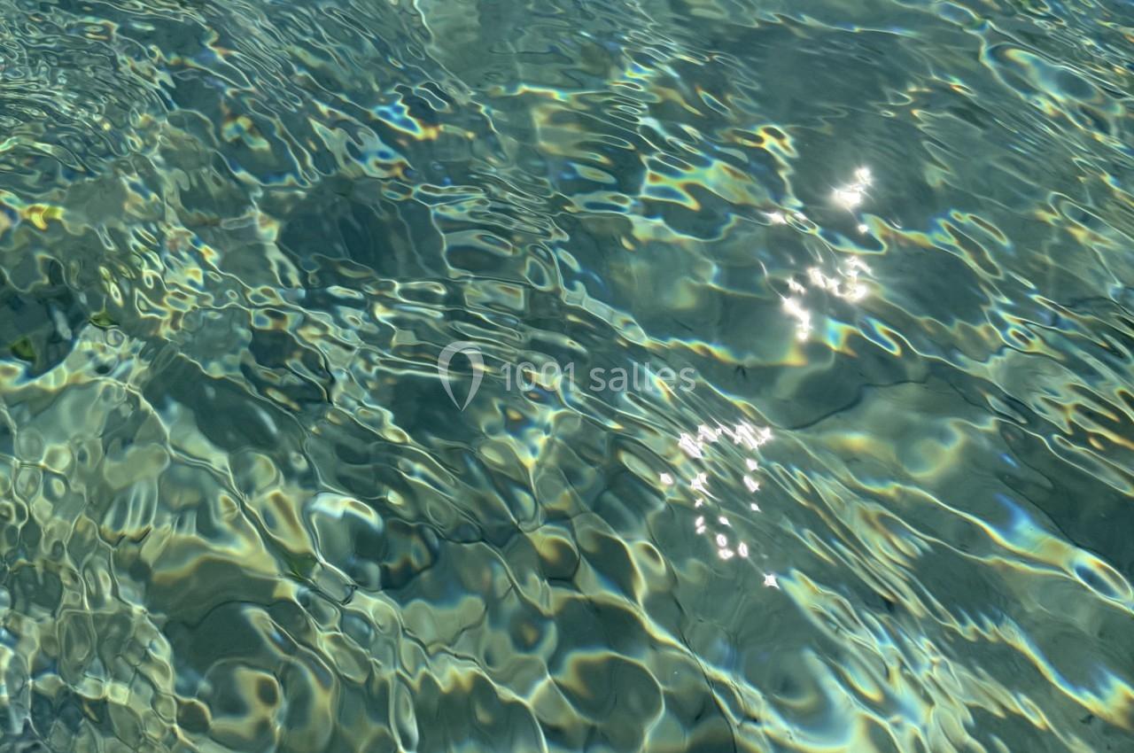Location salle Roquevaire (Bouches-du-Rhône) - Nao Athéna #25 Reflets du soleil sur une surface d'eau claire avec des ondulations et des nuances de bleu et vert.