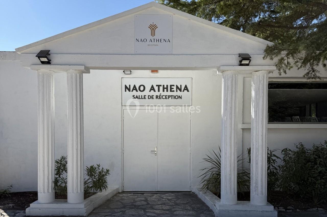 Location salle Roquevaire (Bouches-du-Rhône) - Nao Athéna #26 Façade blanche avec colonnes et porte centrale indiquant ’Nao Athena - Salle de réception’, entourée de végétation.