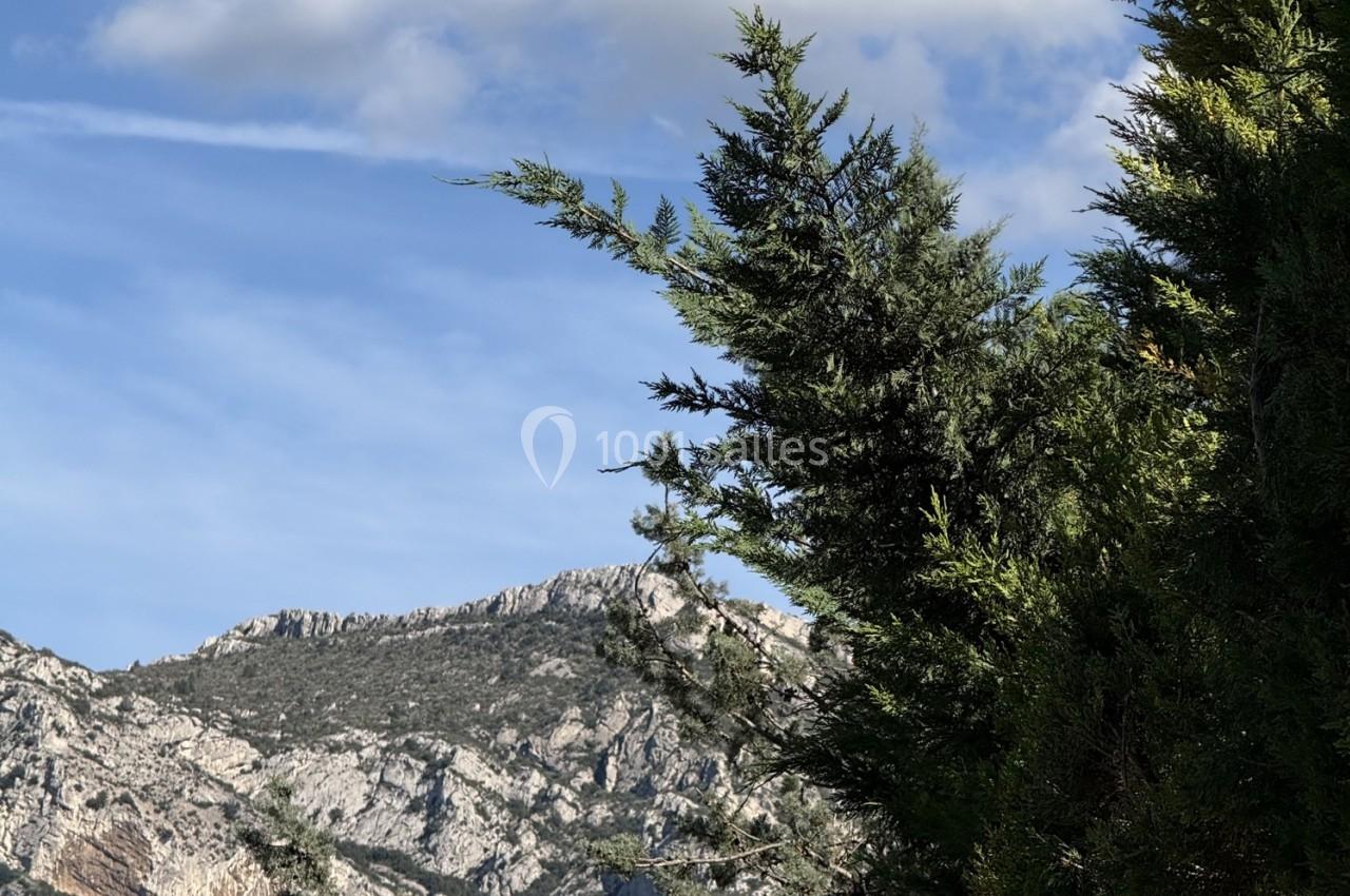 Location salle Roquevaire (Bouches-du-Rhône) - Nao Athéna #36 Paysage de montagne avec un ciel bleu partiellement nuageux et des arbres au premier plan.