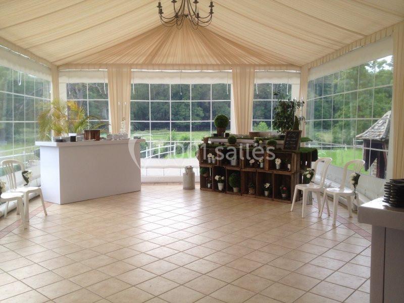 Intérieur d'une tente lumineuse avec sol carrelé, mobilier blanc, étagères décorées et vue sur un jardin verdoyant.