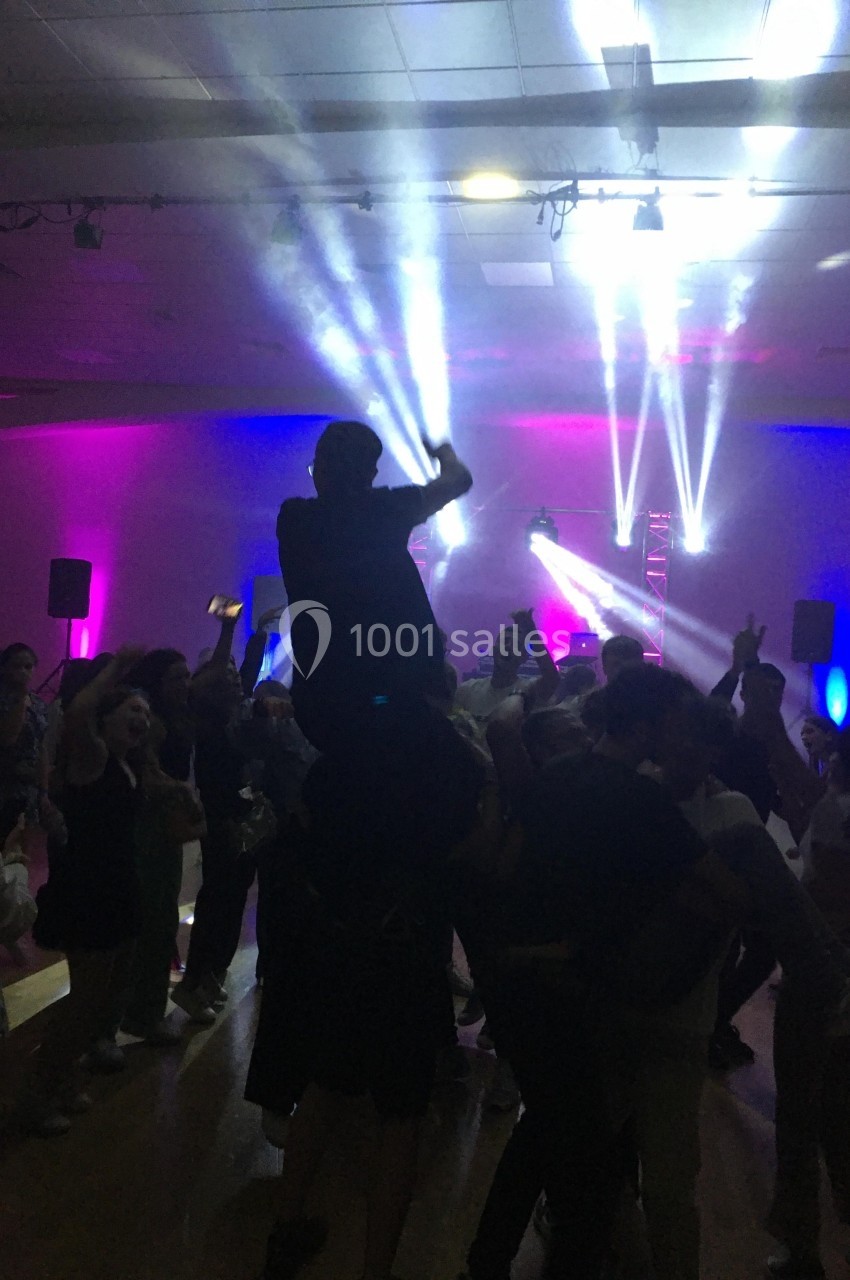 Groupe de personnes dansant sous des jeux de lumière colorés dans une salle sombre.