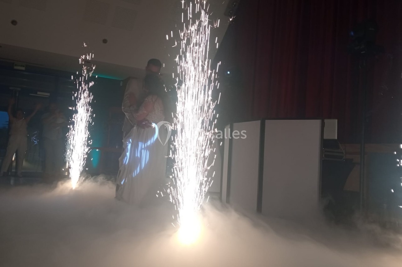 Un couple danse au milieu d'effets pyrotechniques et d'une ambiance de fumée dans une salle sombre.