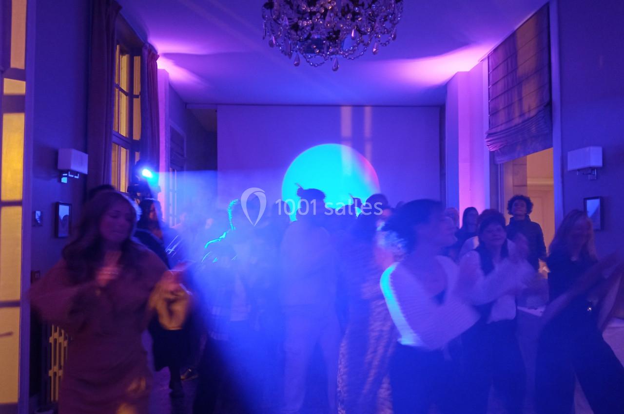 Groupe de personnes dansant dans une salle éclairée par des lumières colorées, ambiance festive.