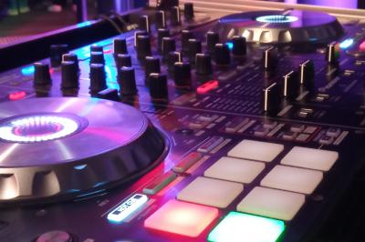 Miniature DJ Linselles (Nord) - AB Evènementiel #12 Mur en briques éclairé par des lumières rouges et vertes avec des enceintes noires sur pieds alignées.