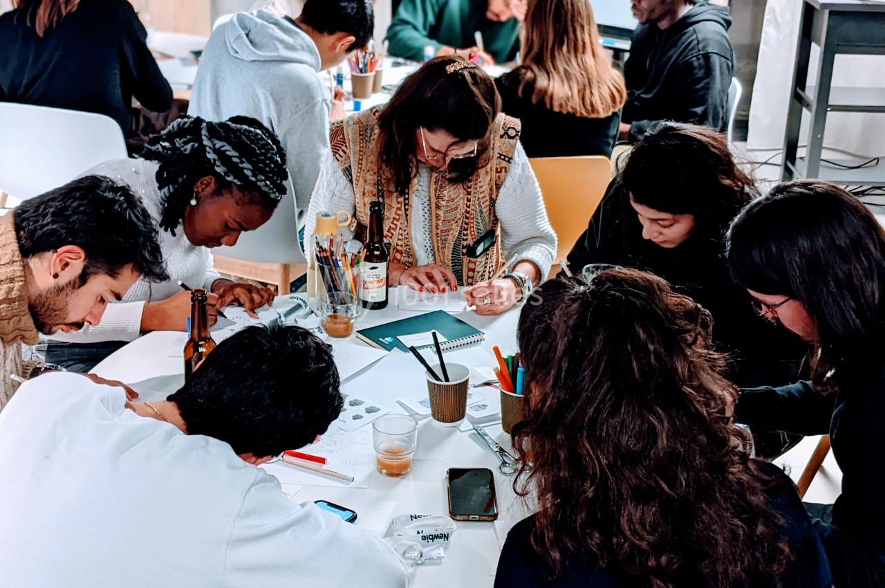 Des personnes assises autour d'une table collaborent sur des activités créatives avec des fournitures et des documents.